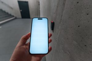 En hand håller en upplyst smartphone nära en kortläsare