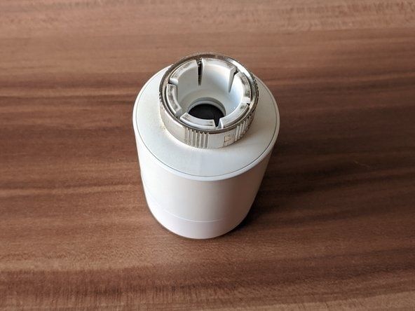 Vit termostatdel för element, fotograferad ovanifrån på ett träbord